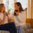 Women eating crackers and talking about menopause while sitting on a couch.
